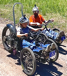Two men on adaptive bikes enjoying the trail