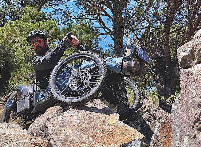 Student riding adaptive bike on rocks