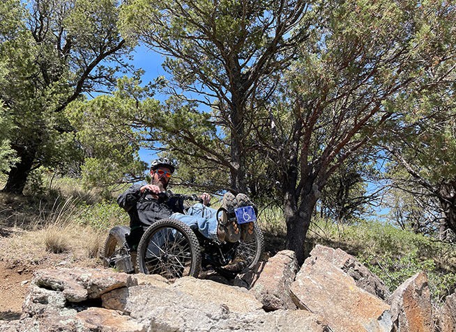 Man on adaptive bike near rocks on trail